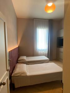 two beds in a room with a window at Villino Bavassano - Dimora Storica in Rimini