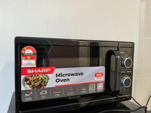 Un horno microondas negro con una caja de comida. en Simfoni Hillview Premium Homestay 02, en Kuah