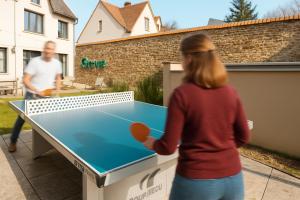 a woman playing a game of ping pong at la Zinguerie de la Plage - plage 300m - babyfoot, arcade, pingpong in Saint-Pair-sur-Mer