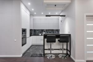 a kitchen with white cabinets and black counter stools at Sea Pearl 1Line in Odesa