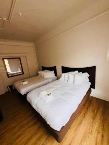 two beds in a room with white sheets and pillows at Riviera Hotel in San Francisco