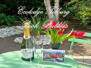 a bottle of wine and two glasses on a table at Ecolodge Tilburg met zwembad in groene oase bij centrum in Tilburg