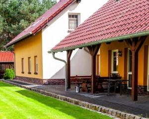 a yellow and white house with a table in front of it at Pension + Apartments Tor zum Spreewald in Lübben