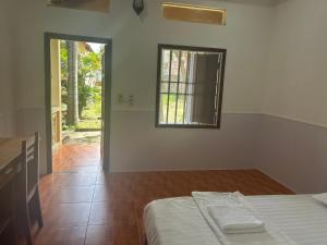 Una habitación blanca con una cama y una ventana. en Bungalow COCO CHILL PQ, en Phu Quoc