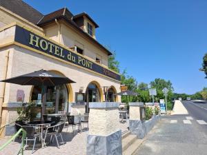 a hotel go point with tables and an umbrella at Hôtel du Pont et Restaurant à Groléjac in Groléjac
