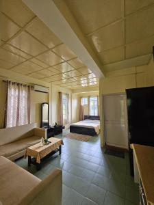 Una sala de estar con un sofá, un televisor y una cama. en Vestawood Orchid Resort, Dawki Meghalaya, en Dawki