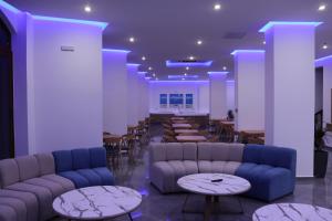 a waiting room with couches and tables and chairs at Oceanis Hotel in Karpathos
