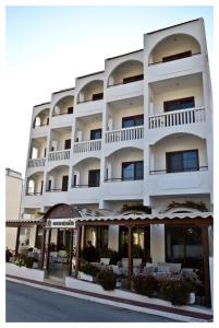 a white building with tables and chairs in front of it at Oceanis Hotel in Karpathos