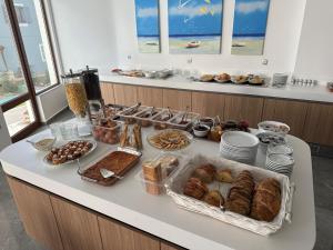 a breakfast buffet with pastries and other foods on a counter at Oceanis Hotel in Karpathos +25 photos