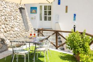 a patio with a table and chairs on the grass at Holidays Perla d'Amalfi - Live the Coast & Private Parking in Amalfi
