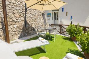 a patio with a table and an umbrella at Holidays Perla d'Amalfi - Live the Coast & Private Parking in Amalfi