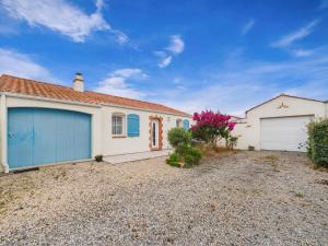 a house with two garage doors on a gravel driveway at Jardin et véranda - Maison 4 adultes 2 enfants in Saint-Hilaire-de-Riez
