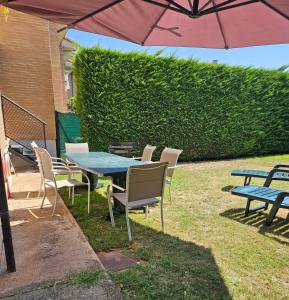 a picnic table and chairs with an umbrella at Casa Entre Viñas, jardin privado con piscina comunitaria in Uruñuela