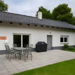 a patio with a table and chairs in front of a white house at Natur pur in Kraiburg am Inn