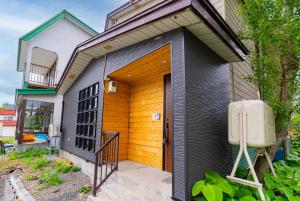 a small house with a wooden door on the side of it at Kotobuki in Otaru
