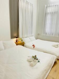 Champagne Homestay في هوى: سريرين بيض في غرفة عليها ورد