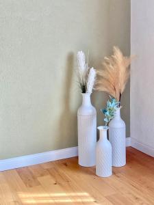 four white vases sitting on a floor with feathers at Chasa ARLU in Samnaun