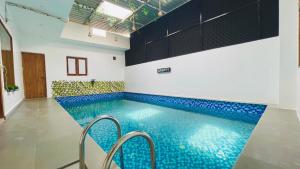 una piscina con azulejos azules en una habitación en Arth Villa, en Noida 5 fotos más