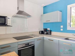 a kitchen with white appliances and blue walls at 354 - Maison neuve en plein cœur de Plévenon. in Plévenon
