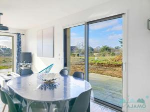 a dining room with a table and a large sliding glass door at 354 - Maison neuve en plein cœur de Plévenon. in Plévenon
