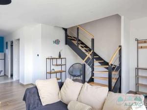 a living room with a couch and a staircase at 354 - Maison neuve en plein cœur de Plévenon. in Plévenon