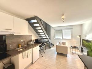 a kitchen and a living room with a stairway at Appartement calme parking in Le Monastère