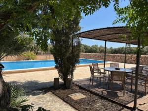 una mesa y sillas bajo una sombrilla junto a una piscina en Finca Albenyeta, en Llucmajor