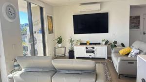a living room with a couch and a flat screen tv at beach pad in Wollongong