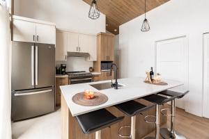 eine Küche mit Spüle und Theke mit Hockern in der Unterkunft Ski Condo & Spa - L'Elegance Des Sommets in Adstock