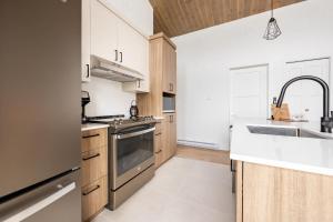 eine Küche mit Holzschränken und einer Spüle in der Unterkunft Ski Condo & Spa - L'Elegance Des Sommets in Adstock