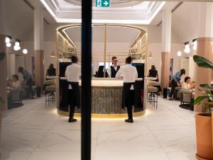 a group of people standing at a bar in a restaurant at Hotel & Spa Oceania Lille Les Augustins in Lille