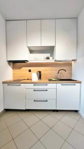 a kitchen with white cabinets and a sink at Komfortowy Apartament in Debrzno
