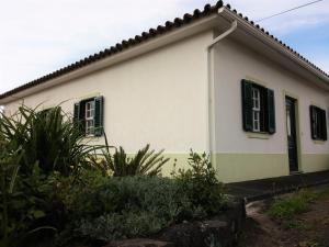 Casa blanca con ventanas con persianas verdes en House Andrade, en Praia do Norte