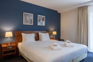 a bedroom with a large bed with two towels on it at Amrâth Grand Hotel Frans Hals in Haarlem