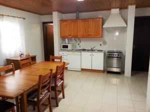 een keuken met een houten tafel en een keuken met witte kasten bij House Andrade in Praia do Norte