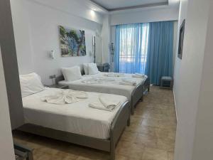 a hotel room with three beds and a window at Oceanis Hotel in Karpathos