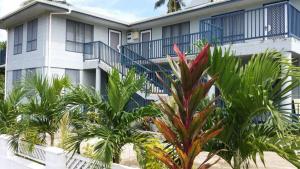 a building with palm trees in front of it at Maninoa Surf Accommodation in Apia