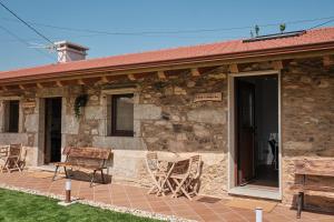 a stone house with chairs on a patio at As casiñas da Figueira by Serendipia Turismo in Pobra do Caramiñal