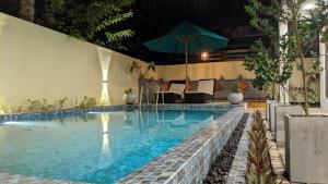 a swimming pool with an umbrella and chairs and a couch at Mayon Beach villa in Tangalle