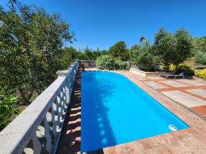 a blue swimming pool on a fence with trees at La Muntanera - Eco-friendly apartment in Figuerola