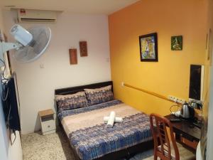 a bedroom with a bed and a desk and a fan at Elephant House Hotel in George Town