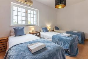 a room with three beds with blue and white sheets at Marmeleira Country House in Carregado +37 photos