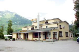 a hotel in a parking lot with a mountain in the background at Hotel Dante in Ponte nellʼAlpi
