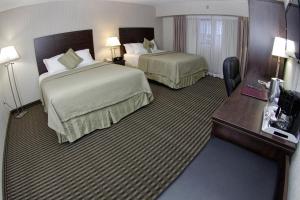 a hotel room with two beds and a desk at Victoria Inn Hotel & Convention Centre Brandon in Brandon