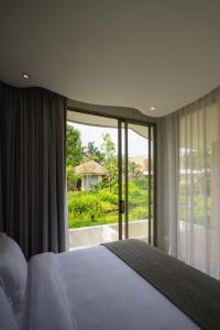a bedroom with a bed and a large window at Mahutsachan Khlong Thom in Krabi town