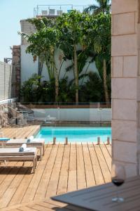 a swimming pool with a wooden deck and a building at Villa Alma Eilat in Eilat