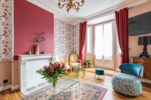 a living room with a fireplace and red walls at Le Louis XV Halte à Reims centre in Reims