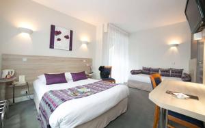 a hotel room with a large bed and a table at Logis Hôtel Auberge de la Rose in Doué-la-Fontaine
