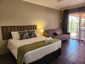 a bedroom with a large bed and a couch at Tree Orchid in Polokwane