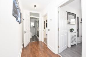 un pasillo de una casa con paredes blancas y suelo de madera en Big Ben 2 Bed, en Londres